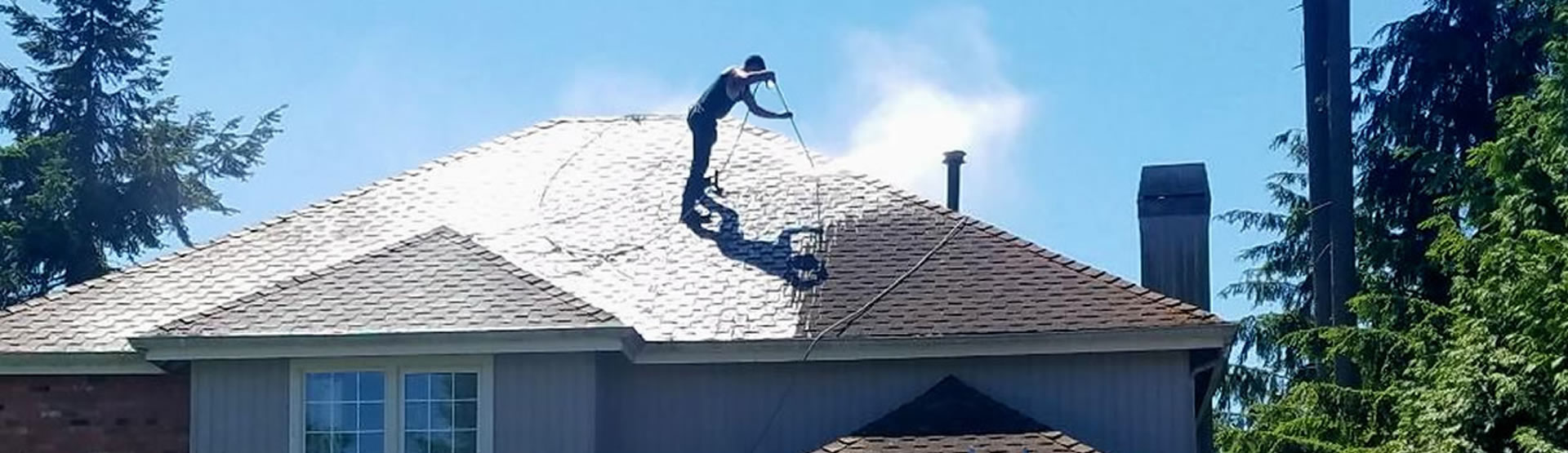 A roofer on top of a house repairing the roof.